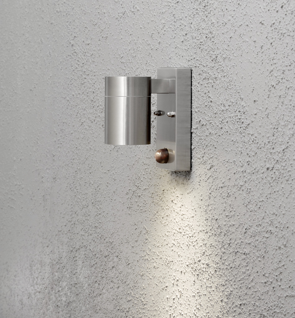 Modena Sølv udendørslampe Fra Konstsmide - Lampens stilrene og moderne design smelter ind i alle facader og tænder automatisk, når den registrerer bevægelse, hvilket giver ekstra sikkerhed i entre og entre.