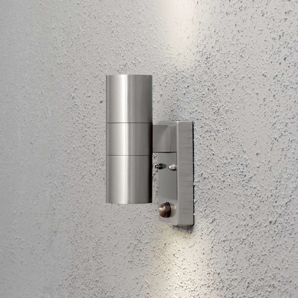 Modena Sølv udendørslampe Fra Konstsmide - Lampens stilrene og moderne design falder ind i alle facader og tænder automatisk, når den mærker bevægelse, hvilket giver ekstra tryghed i entre og entre.