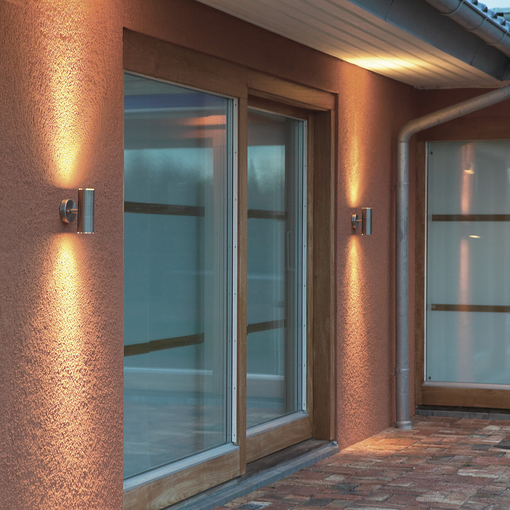 Modena Sølv udendørslampe Fra Konstsmide - Skab en elegant og moderne belysningsløsning til din facade med denne væglampe i rustfrit stål, der lyser både op og ned.