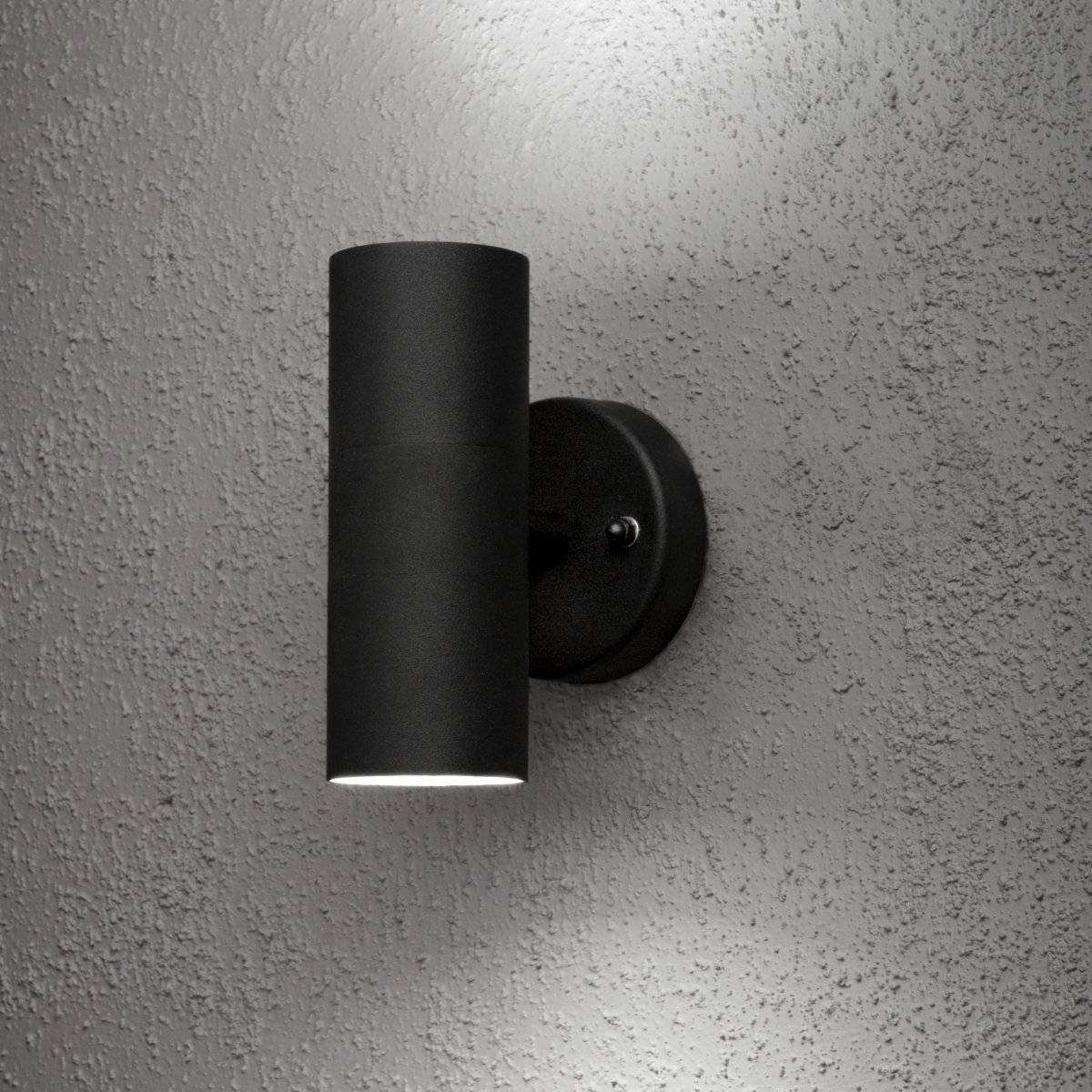 Modena Sort udendørslampe Fra Konstsmide - Lampen spreder lyset b&aring;de opad og nedad og skaber et dekorativt lysbillede, der fremh&aelig;ver facaden og giver en im&oslash;dekommende f&oslash;lelse udend&oslash;rs.