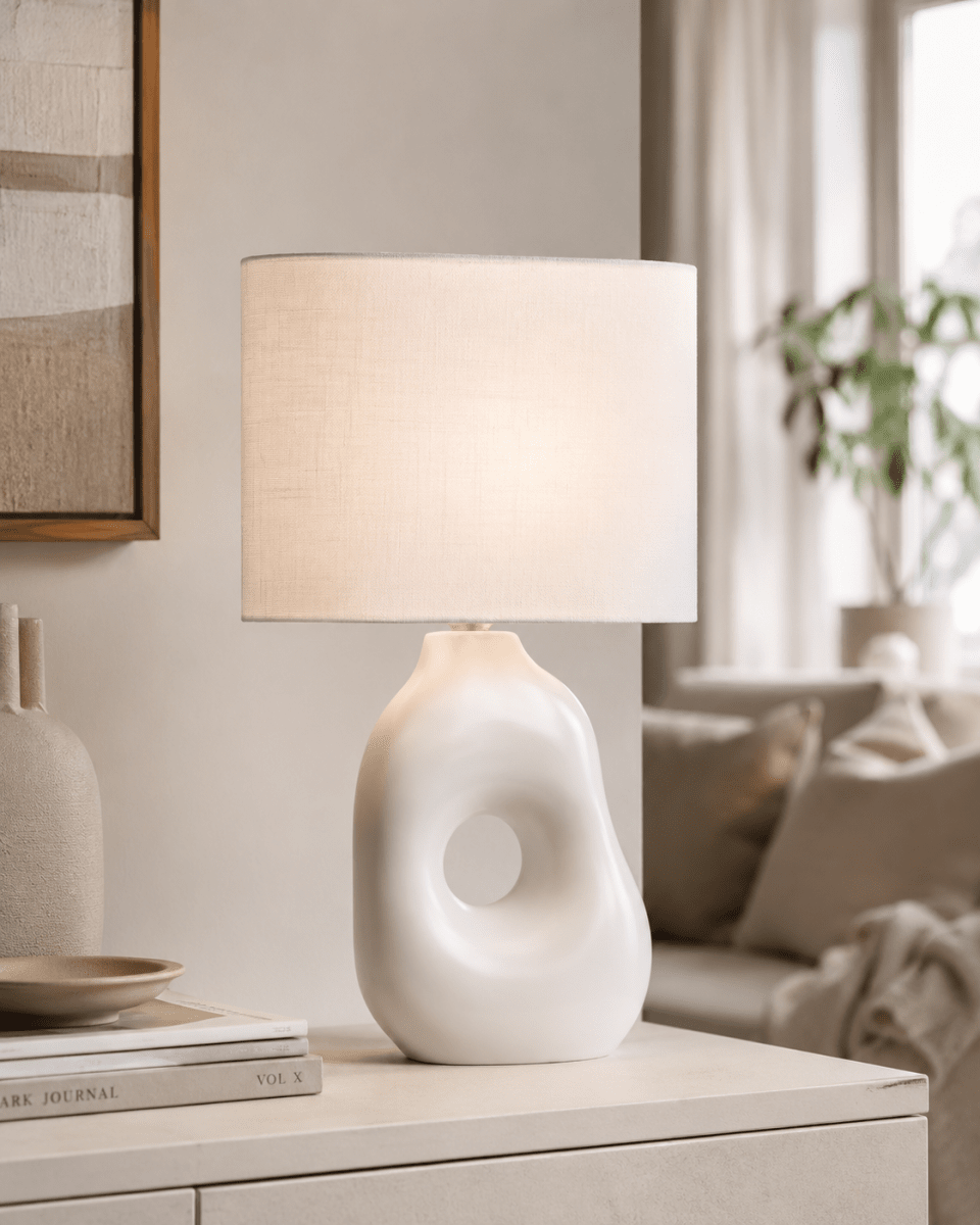Pikazo 45cm Hvid bordlampe Fra Lampan - Pikazo bordlampen har en unik keramisk base med en skulpturel form og et dekorativt, sammenh&aelig;ngende h&aring;r, kombineret med en hvid og oval h&oslash;rsk&aelig;rm.