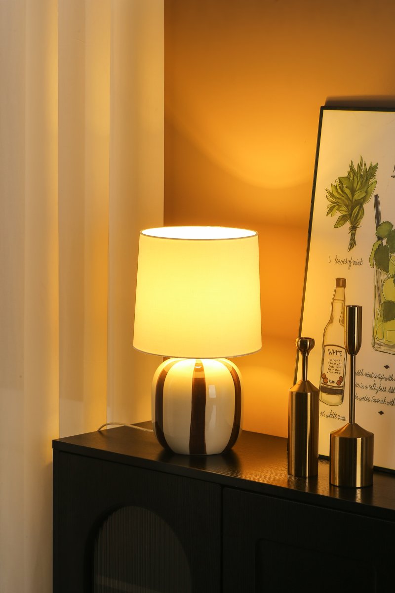 Pholca 38cm Hvid/brun bordlampe Fra Nordic Lighting - Lampefoden er lavet af keramik med en cremehvid base og brune striber, der skaber liv og karakter.