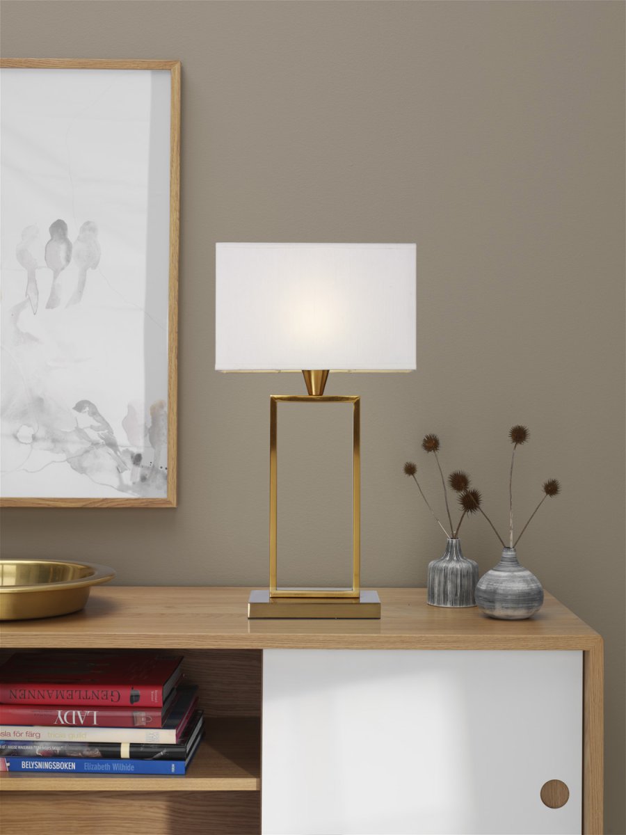 Kensington 50cm Messing bordlampe Fra Cottex - Den stilrene metalramme skaber en luftig og moderne følelse, mens den hvide tekstilskærm spreder et blødt og behageligt lys.