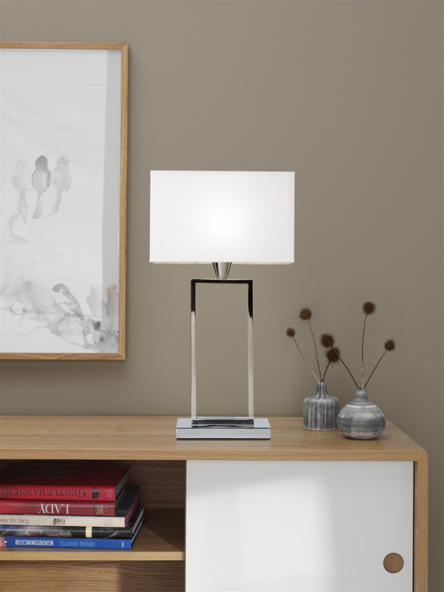 Kensington 50cm Chrom bordlampe Fra Cottex - Den stilrene metalramme skaber en luftig og moderne følelse, mens den hvide tekstilskærm spreder et blødt og behageligt lys.