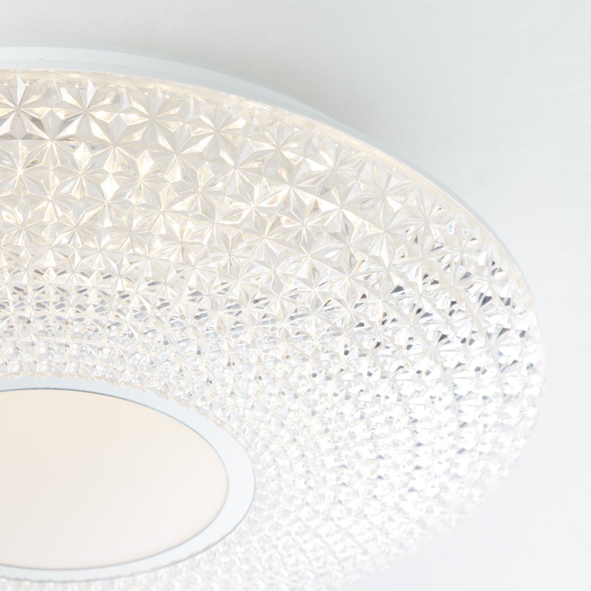 Lucian Ø40 Hvid plafond Fra Brilliant - LED-panelet omfavnes af den klare sk&aelig;rm med sm&aring; prismer, der skaber et smukt lysm&oslash;nster i rummet, n&aring;r lampen er t&aelig;ndt.