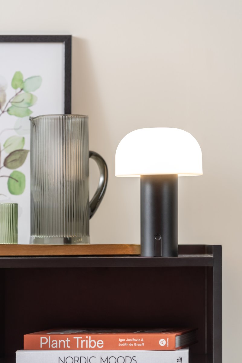 Luca LED 22cm Sort bærbar Fra Leitmotiv - Den er lavet af metal med en matsort finish og har en mælkehvid plastikskærm, der spreder et blødt og behageligt lys.