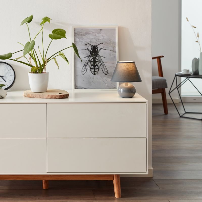 Primo 23cm Mørkegrå bordlampe Fra Brilliant - Den er lavet af tekstil og keramik og giver et behageligt lys.